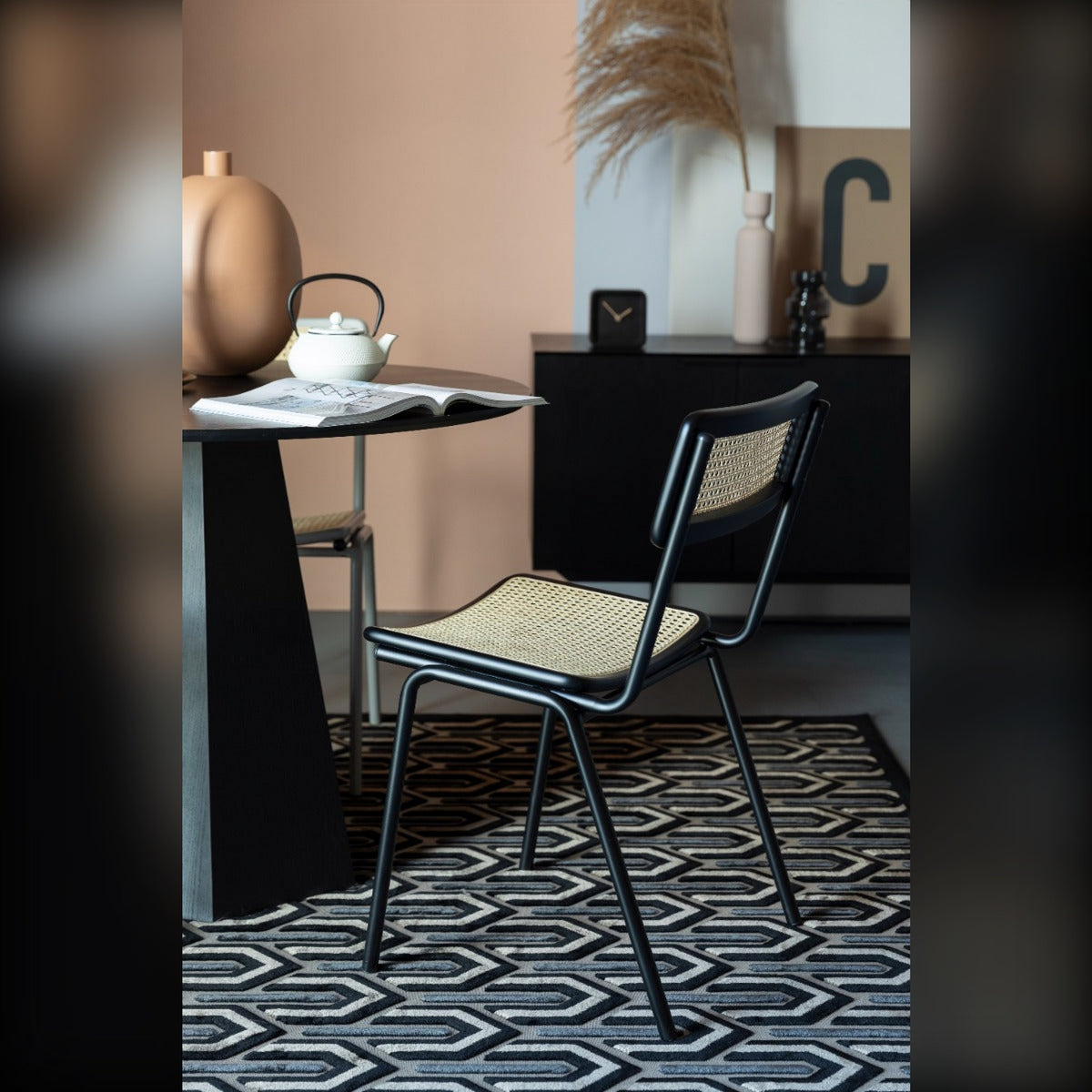 Dining Chair Jort Natural Black Domestica – Lifestyle – Beside a Round Black Table on a Patterned Rug