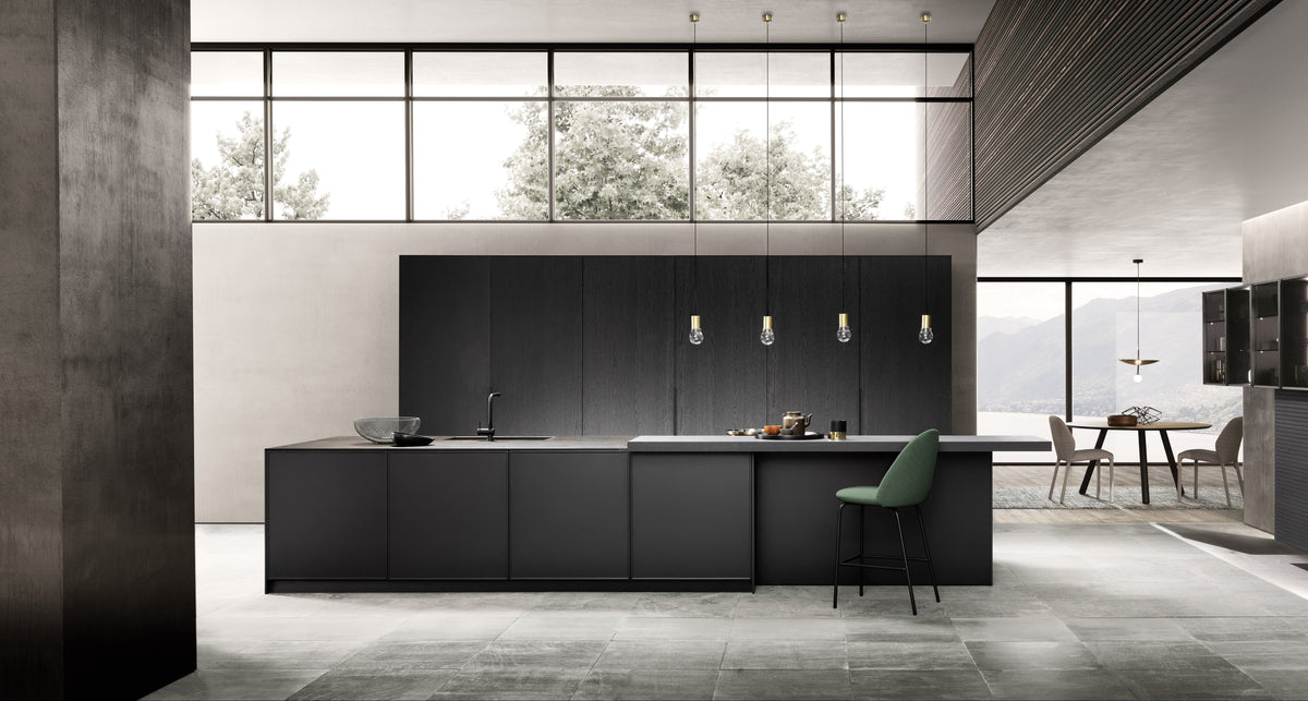 Modern kitchen with black cabinetry and a green chair.