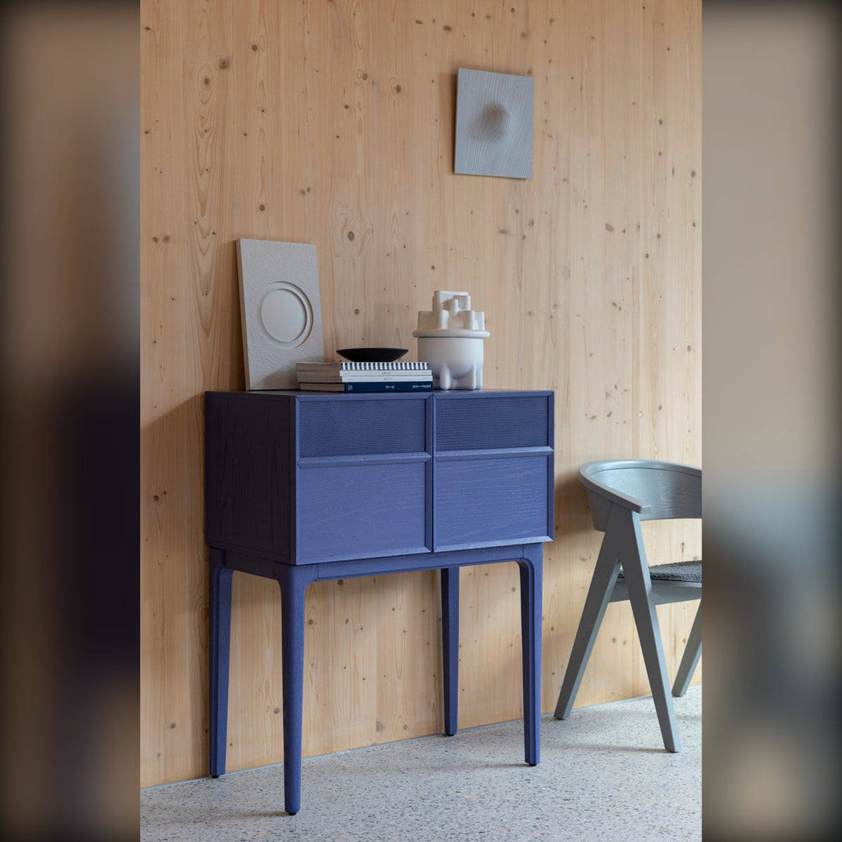 Cabinet June Ocean Purple Domestica – Lifestyle – Against a Wooden Wall with Chair