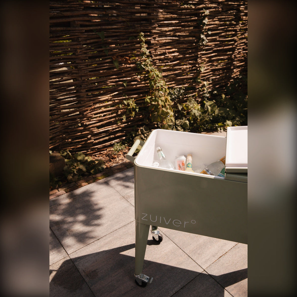 Cooler Be Cool Green Domestica – Lifestyle – Open with Drinks by a Woven Fence